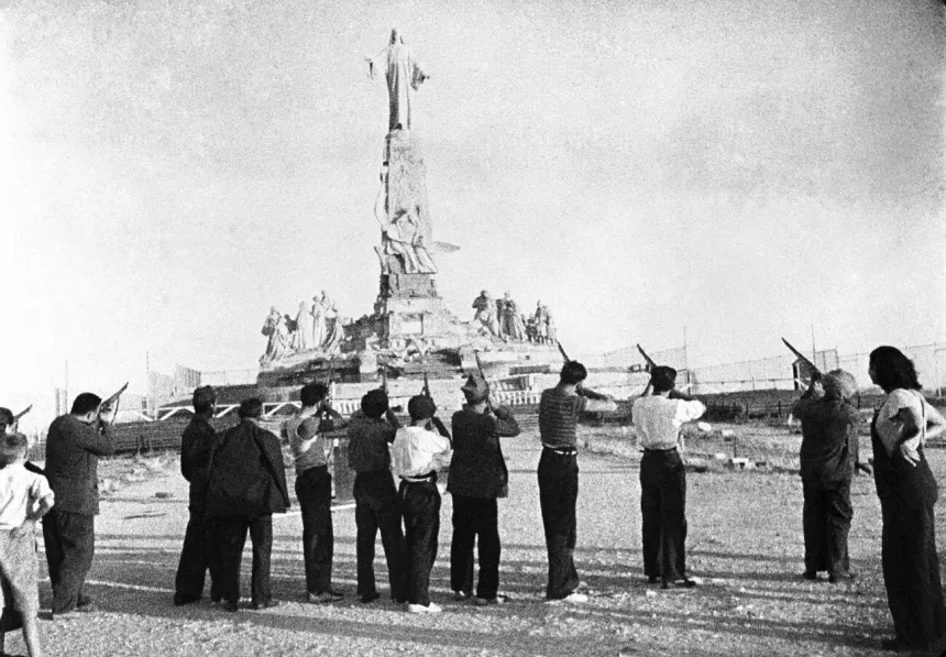 Gammelt fotografi av menn som skyter på en statue av Jesus under den spanske borgerkrigen