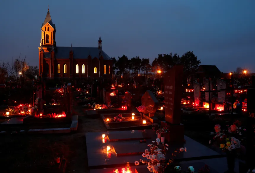 Lys og blomster på en kirkegård ved en kirke