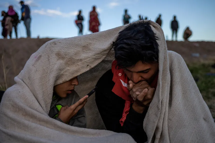 To migranter, far og sønn, holder varmen under et teppe